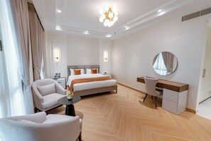 A hotel room with a bed, a desk, a chair, a round mirror, and a ceiling light fixture.