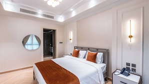 A modern hotel room with a large bed, bedside tables, a mirror, and a phone on the nightstand. - Artan Residence & Suites (Doha)