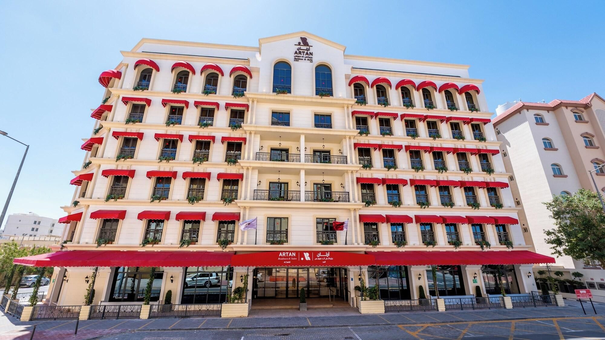 A multi-story hotel with a red awning and balconies.