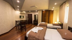 Habitación de hotel con dos camas, un escritorio y un armario.
