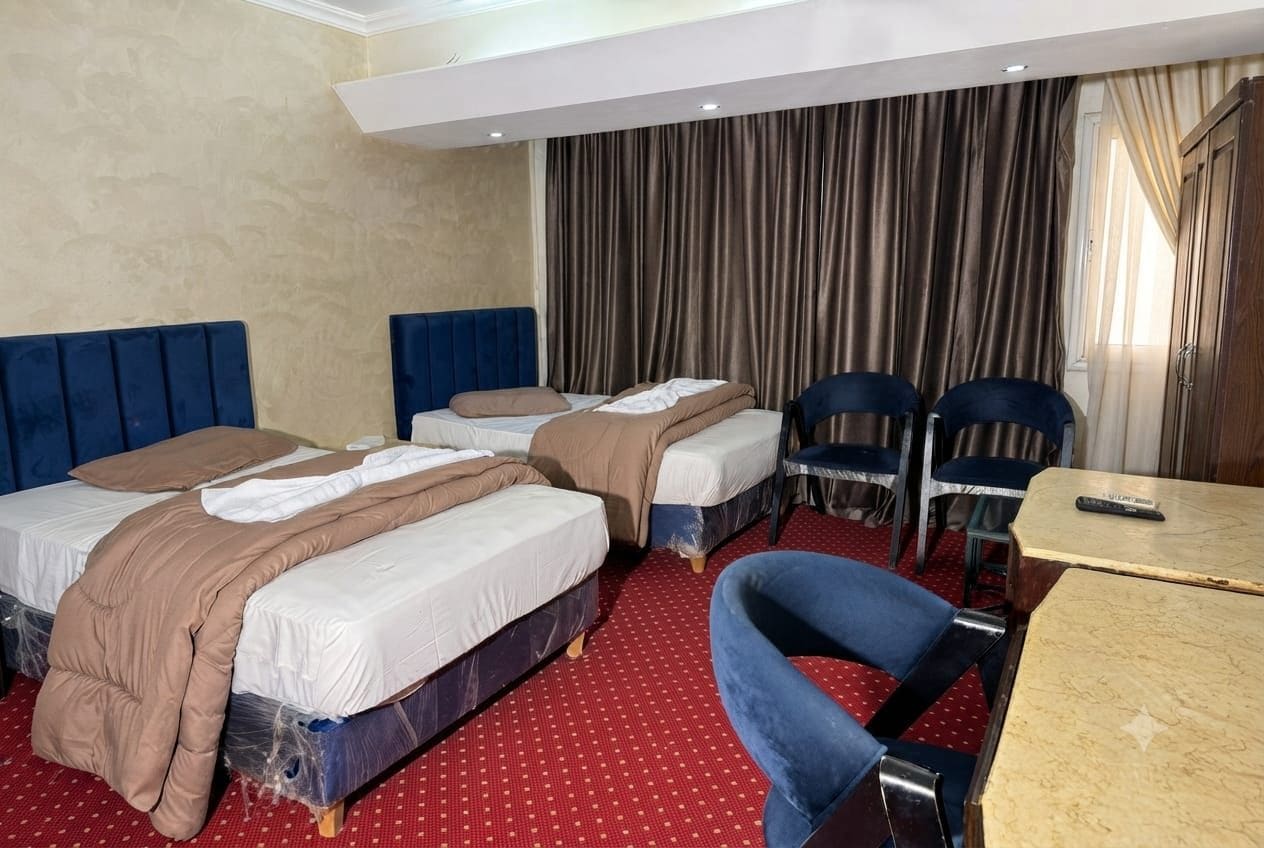 A hotel room with two beds, a desk, and a chair.