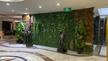 Un vestíbulo con una pared verde, piso de mármol y una estatua.