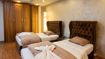 A hotel room with two beds, a wardrobe, and a bedside lamp.