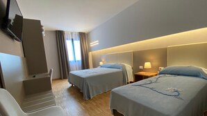 A hotel room with two beds, a TV mounted on the wall, a chair, and a window with curtains. - Delta Park (Porto Viro)