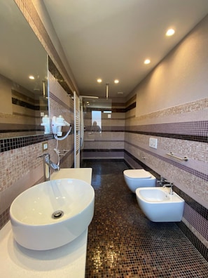 Un baño moderno con un lavamanos grande, dos lavamanos más pequeños y un espejo.