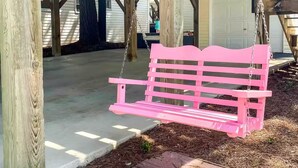 A wooden structure with a pink swing bench, a covered area with a metal roof, and a staircase. - Emmas Beach Hut 2 KING BEDS 3 min to beach (Myrtle Beach)