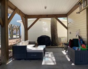A covered outdoor seating area with a bench, a table, and a grill. - Emmas Beach Hut 2 KING BEDS 3 min to beach (Myrtle Beach)