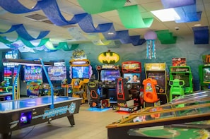 Ein Raum mit Spielautomaten, einem Billardtisch und farbenfroher Dekoration.