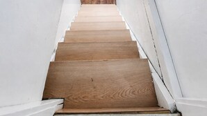 A staircase with wooden steps leading upwards, white walls, and a wooden beam ceiling. - Central Moncton 2BR | Walk, Pets & Parking (Moncton)