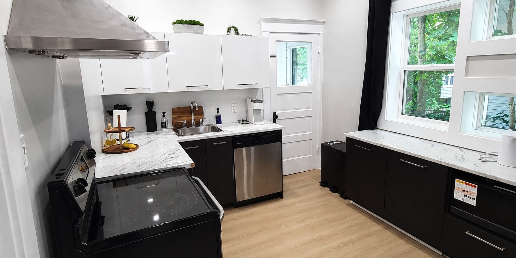 Une cuisine moderne avec des meubles blancs, une cuisinière noire et un lave-vaisselle.