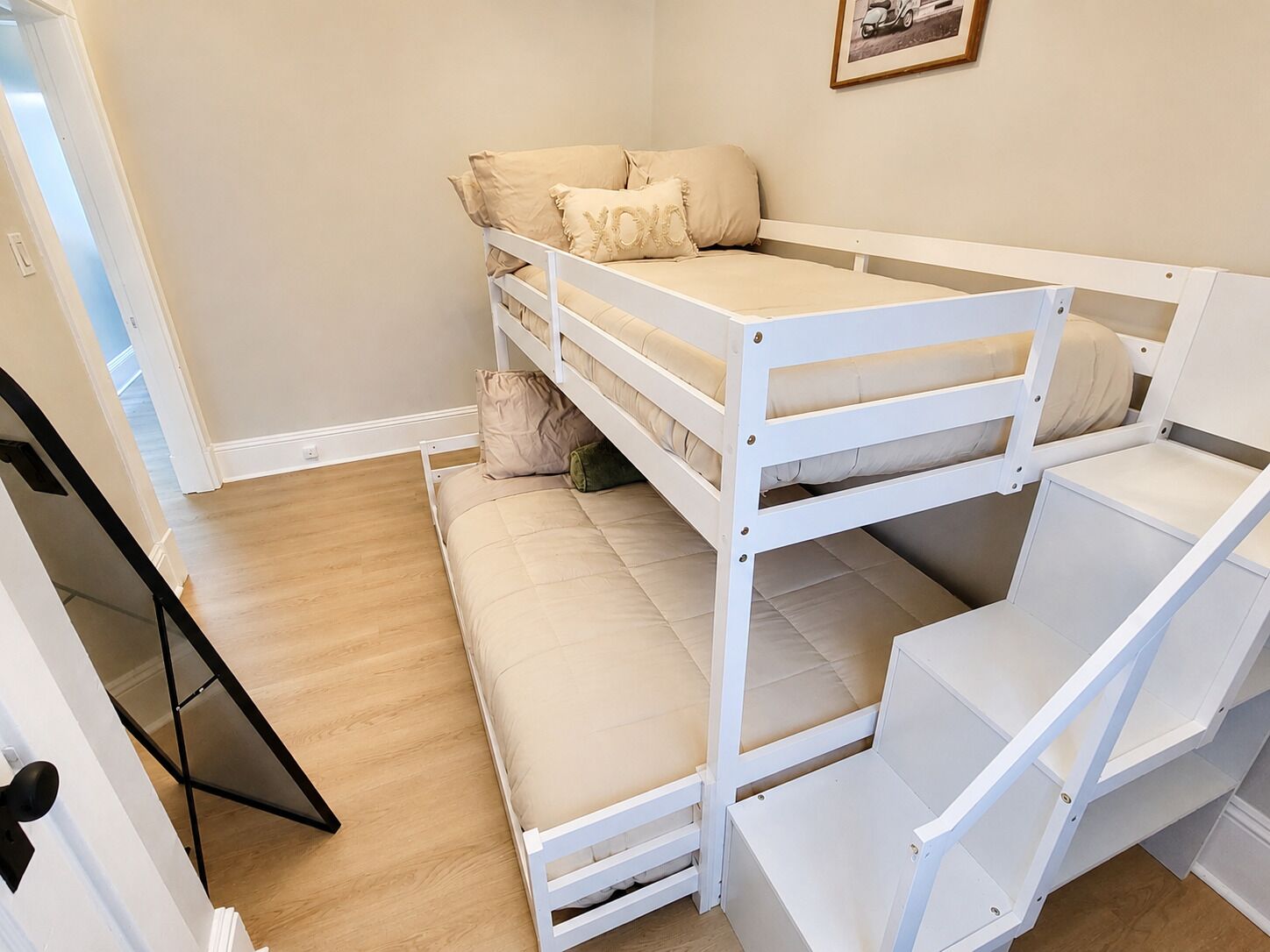 A bunk bed with a mattress and pillows, a wooden floor, and a door.