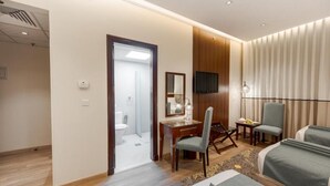 A hotel room with a bed, a desk, a chair, a television, and a bathroom visible through an open door. - Maysan Rotana El Mysk Fully Renovated (Madinah)