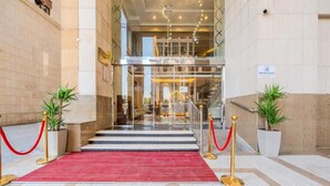 A hotel entrance with a red carpet, glass doors, and a staircase leading to the upper floor. - Maysan Rotana El Mysk Fully Renovated (Madinah)