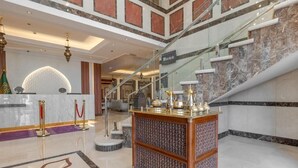 A lobby with a reception desk, a staircase, and a decorative cabinet. - Maysan Rotana El Mysk Fully Renovated (Madinah)