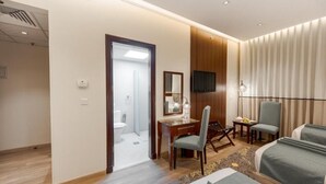 A hotel room with a bed, a desk, a chair, a television, and a bathroom visible through an open door. - Maysan Rotana El Mysk Fully Renovated (Madinah)