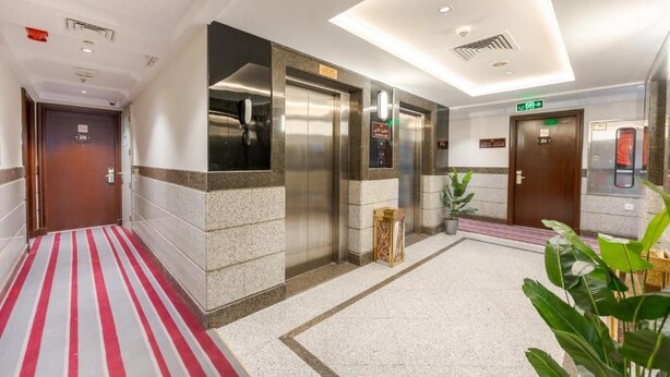 A hotel lobby with a red and white striped carpet, elevators, a reception desk, and a potted plant. - Maysan Rotana El Mysk Fully Renovated (Madinah)