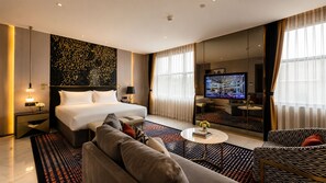 Una habitación de hotel con una cama grande, un sofá, un televisor y un espejo.