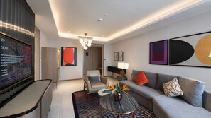 A modern living room with a sofa, armchairs, a coffee table, and a TV.