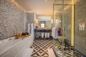 Un baño moderno con piso de diseño geométrico, cabina de ducha de vidrio y espacio para lavamanos de mármol.