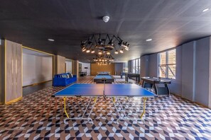 Una habitación con mesa de ping pong, mesa de billar y mesa de futbolín.