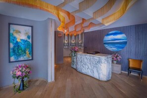 A reception area with a marble counter, a large circular painting, and a wooden floor.