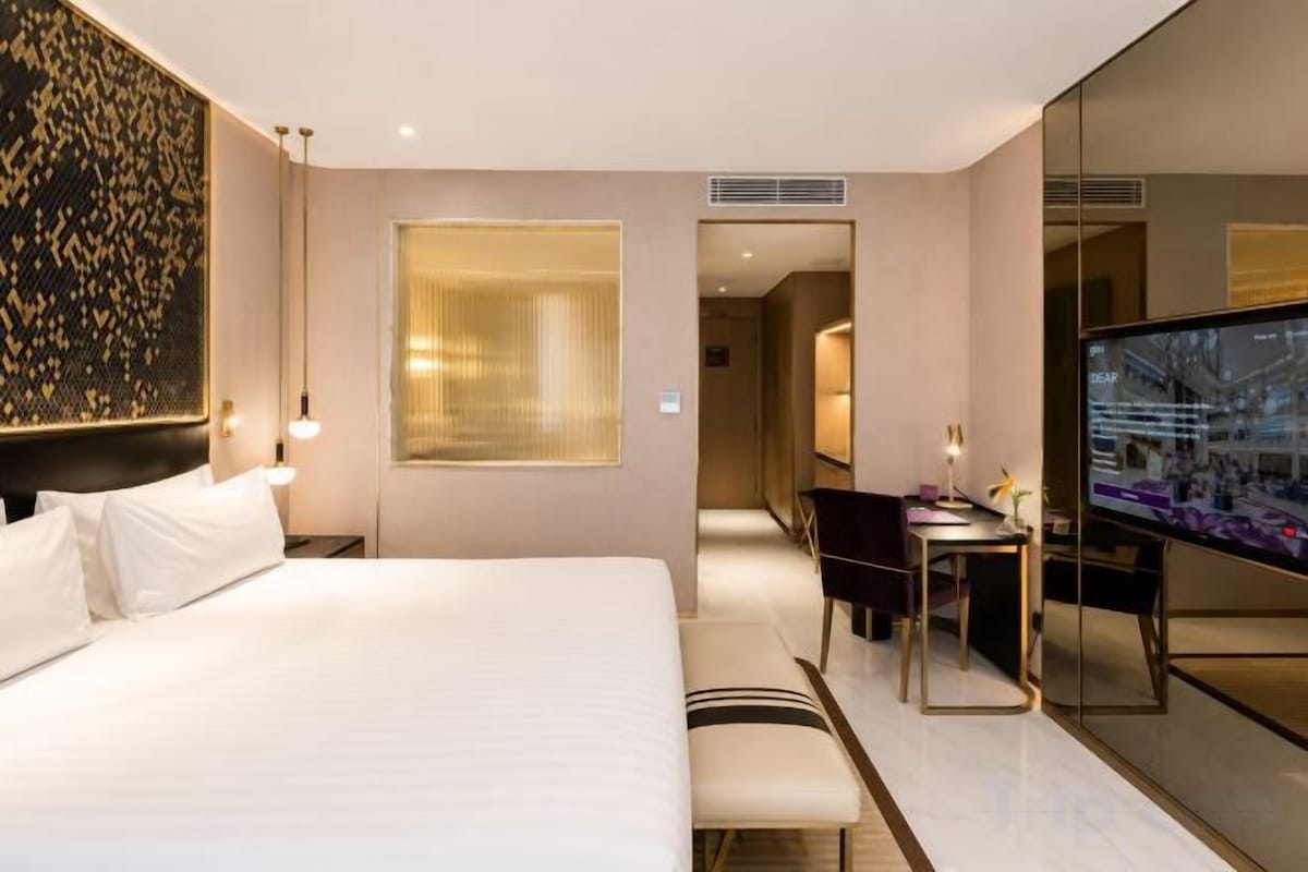 A hotel room with a large bed, a desk, and a television.