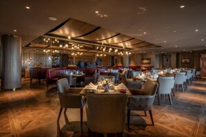Un restaurante con varias mesas y sillas, una zona de bar y un diseño de techo moderno.