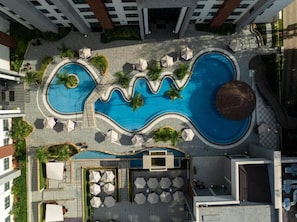An aerial view of a hotel with a unique wavy pool design, outdoor seating areas, and a central water feature. - Glee Nairobi Hotel (Nairobi)