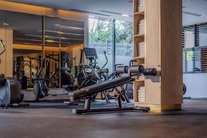 A gym with exercise equipment, a mirrored wall, and a wooden column. - Glee Nairobi Hotel (Nairobi)