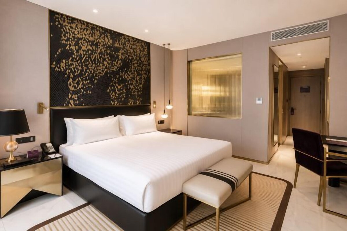 Habitación de hotel con una cama grande, mesitas de noche, un escritorio y una silla.