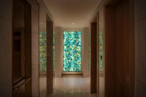 A hallway with a large stained glass window at the end, leading to a room. - Glee Nairobi Hotel (Nairobi)