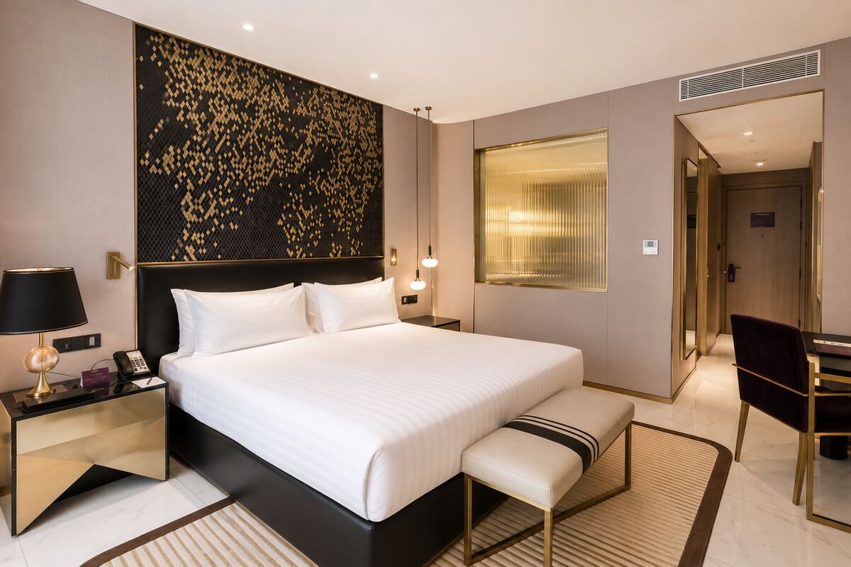 Una habitación de hotel moderna con una cama grande, mesitas de noche, un escritorio y una silla.