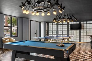A pool table with a blue felt surface, a billiards cue, and a set of balls.