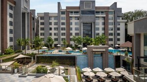 Un hôtel à étages, doté de plusieurs piscines extérieures et de chaises longues.