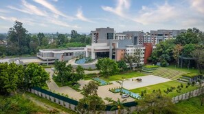 A modern building complex with multiple structures, a central courtyard with a pool, and surrounding greenery.