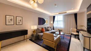 A modern hotel room with a sofa, armchair, coffee table, TV, and artwork on the walls. - Glee Nairobi Hotel (Nairobi)
