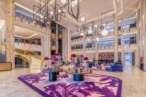A spacious lobby with a grand staircase, modern lighting fixtures, and a central floral arrangement. - Glee Nairobi Hotel (Nairobi)