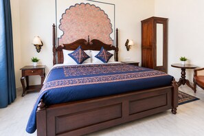 A bedroom with a large bed, two bedside tables, a wardrobe, and a decorative headboard. - Dera Jaipur (Jaipur)