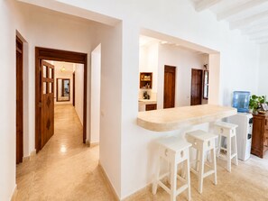 Una cocina con barra, taburetes y dispensador de agua.