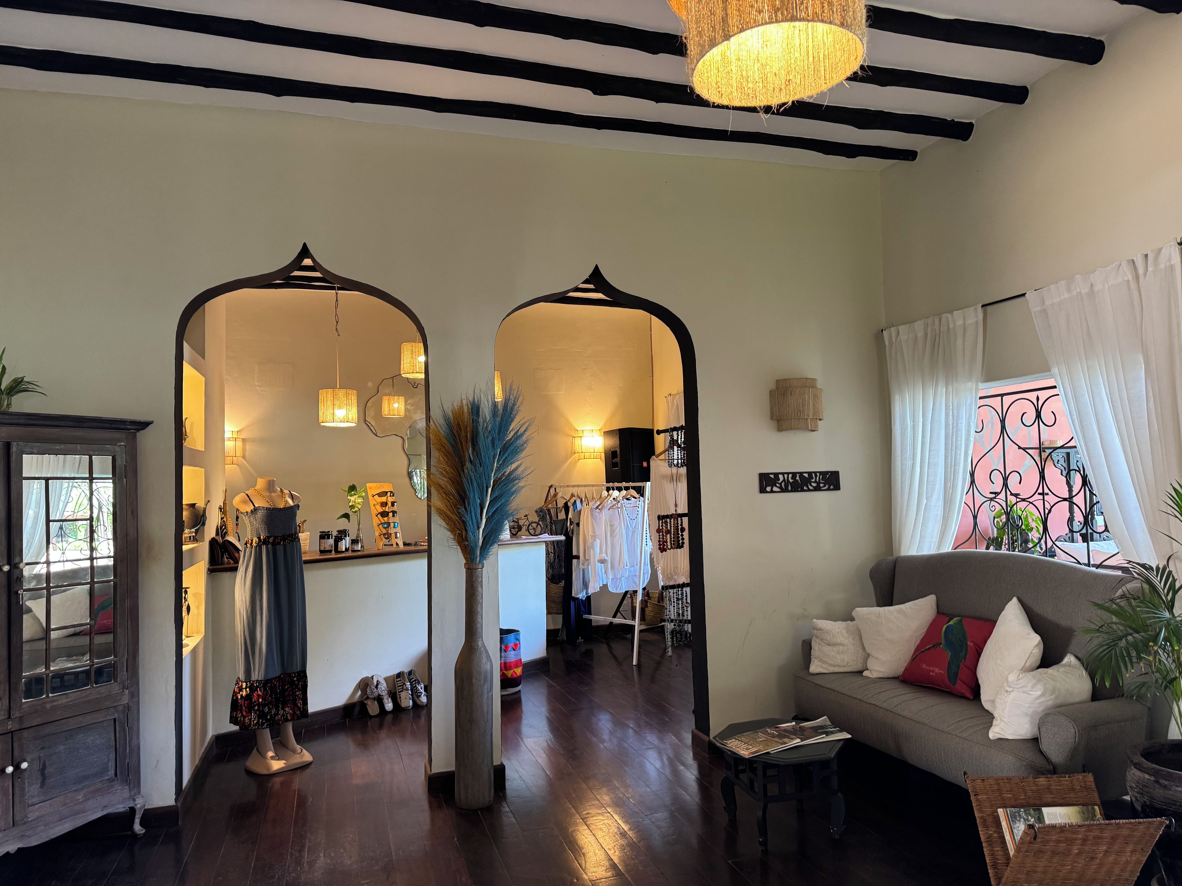 A room with a wooden floor, a sofa, a mirror, and a hanging light fixture.