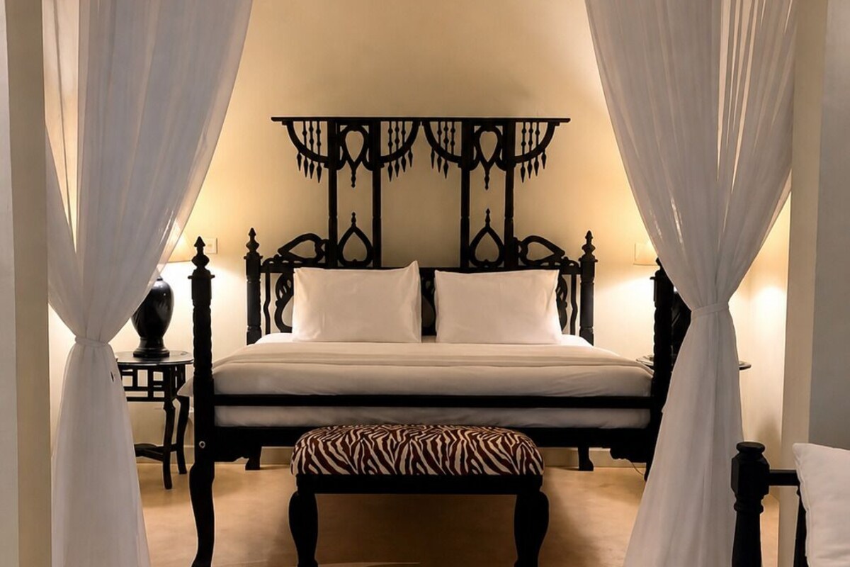 A bedroom with a bed, a bench, and a table.