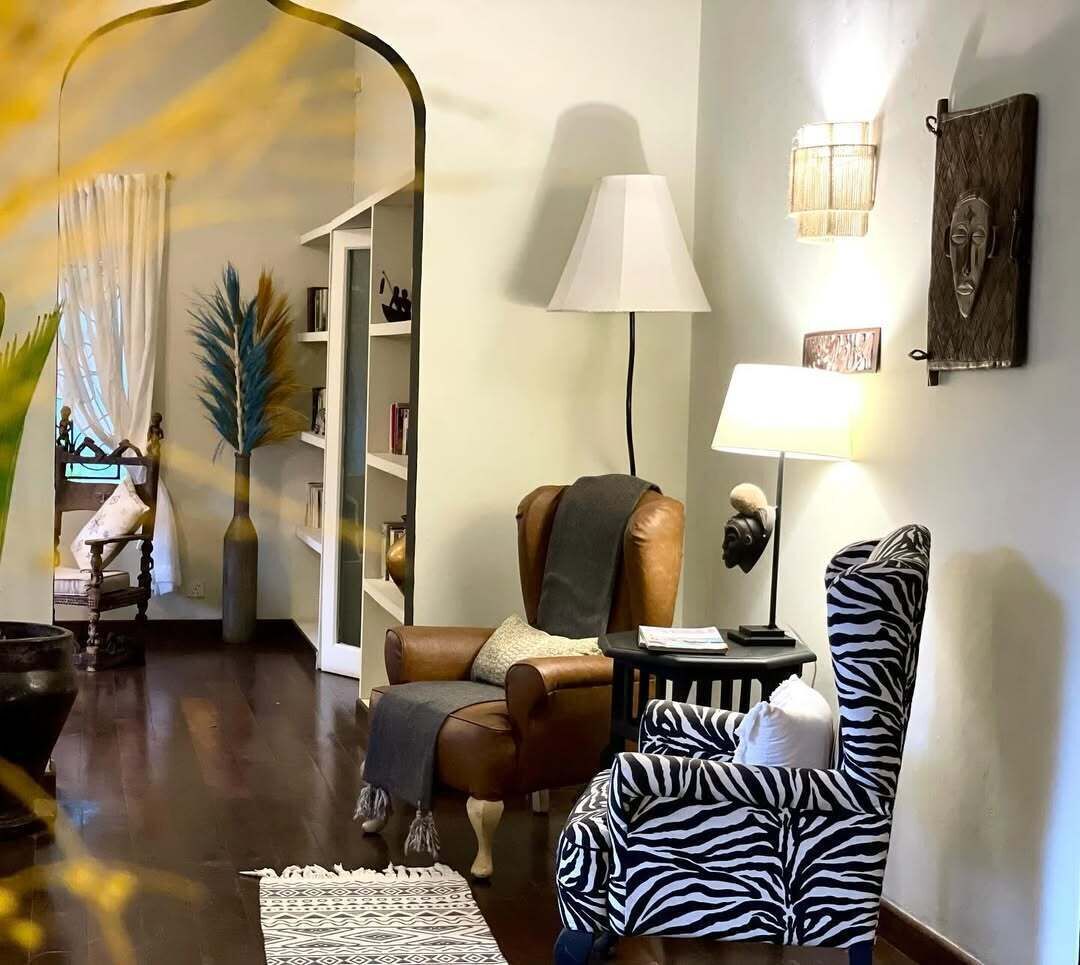 A living room with a brown leather sofa, a zebra-patterned chair, a small round table, and a lamp.