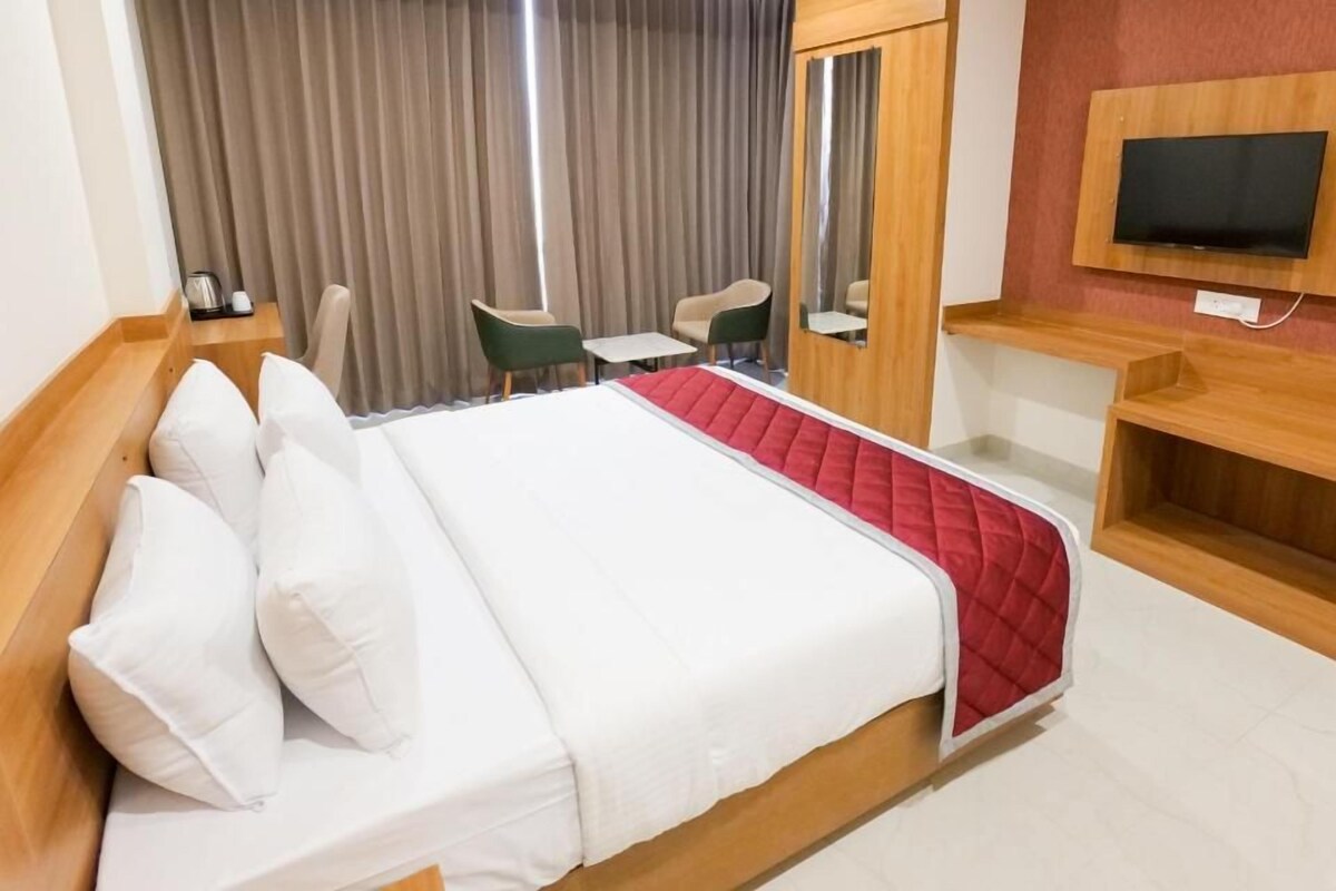 A hotel room with a bed, a TV mounted on the wall, a desk, and a chair.