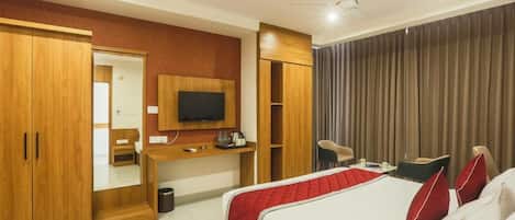 A hotel room with a bed, a desk, a television, and a wardrobe.