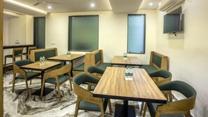 Une salle de conférence dotée de tables en bois et de chaises recouvertes d’un tissu vert, et équipée de la climatisation et d’un ventilateur de plafond.