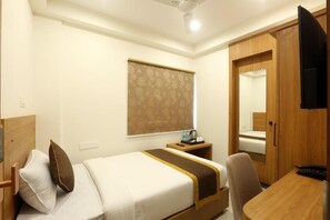 A hotel room with a bed, bedside table, chair, wardrobe, and a television. - The Hoften Sterling Plaza Near BLR Airport (Bengaluru)