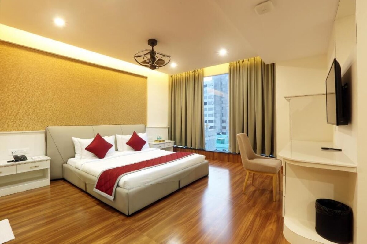 A hotel room with a large bed, a desk, a chair, and a TV.