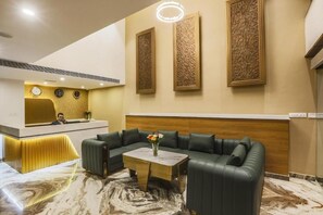 A modern reception area with a reception desk, a leather sofa, and a marble floor. - The Hoften Sterling Plaza Near BLR Airport (Bengaluru)