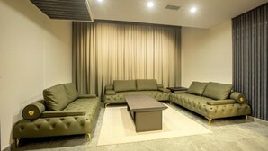 Un salon moderne avec un canapé d’angle, une table basse et une grande fenêtre agrémentée de rideaux.