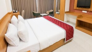 Une chambre d’hôtel avec un lit, un téléviseur fixé au mur, un bureau et une chaise.